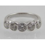 An 18ct white gold and five stone rub-over diamond ring.