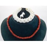 A coral beaded necklace, together with a snake vertebra bangle. (2)