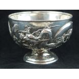 A Chinese white metal bowl, embossed with a continuous design of dragons chasing a flaming pearl,