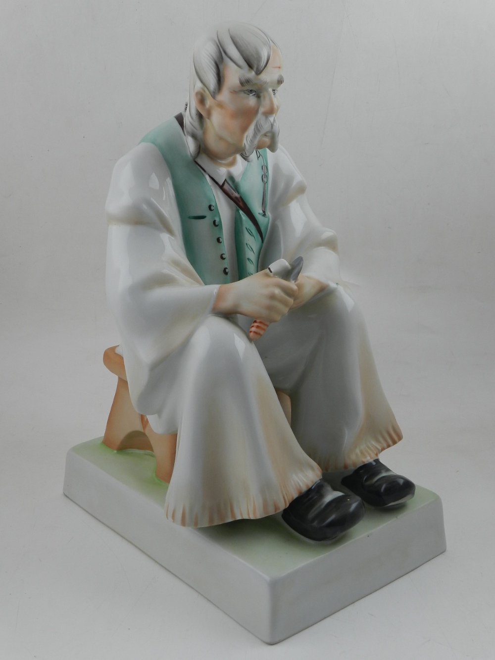 A large Zsolnay porcelain model of a seated elderly shoemaker. H. 33cm