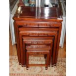 A nest of four Chinese hardwood tea tables with geometric carved friezes on squared legs.