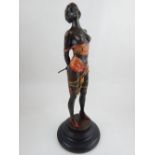 A cold painted bronze figure of a dominatrix, mounted on a circular stepped base.