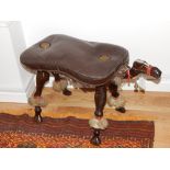 A hardwood camel stool, the a brown leather seat, W. 85cm.