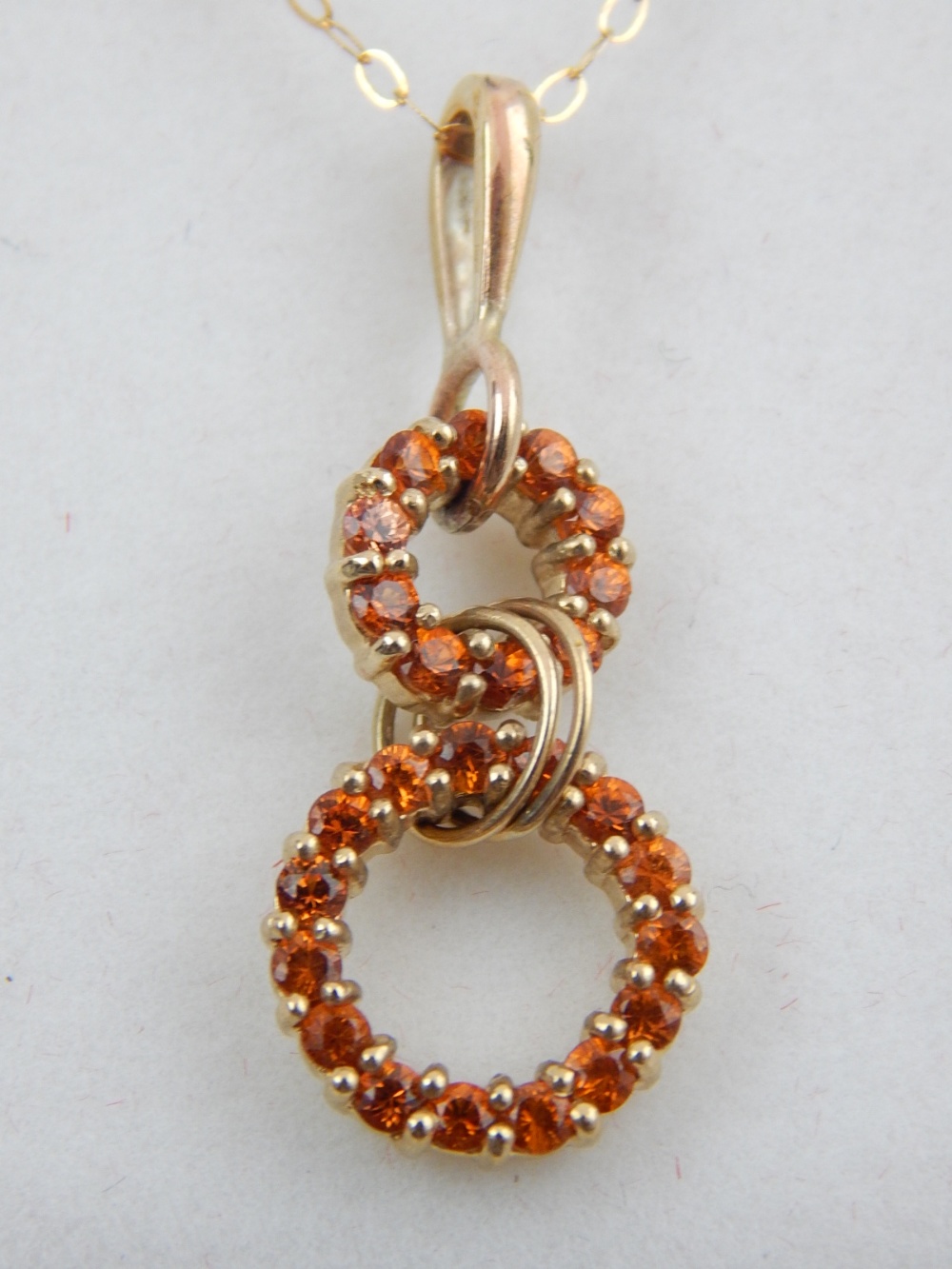 A 9ct yellow gold Maderia garnet drop pendant, suspended on a 9ct yellow gold chain.