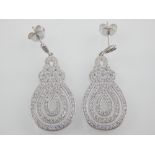 A pair of white metal cubic zirconia drop earrings.
