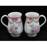 A pair of porcelain baluster tankards each decorated in the famille rose style with floral swags and
