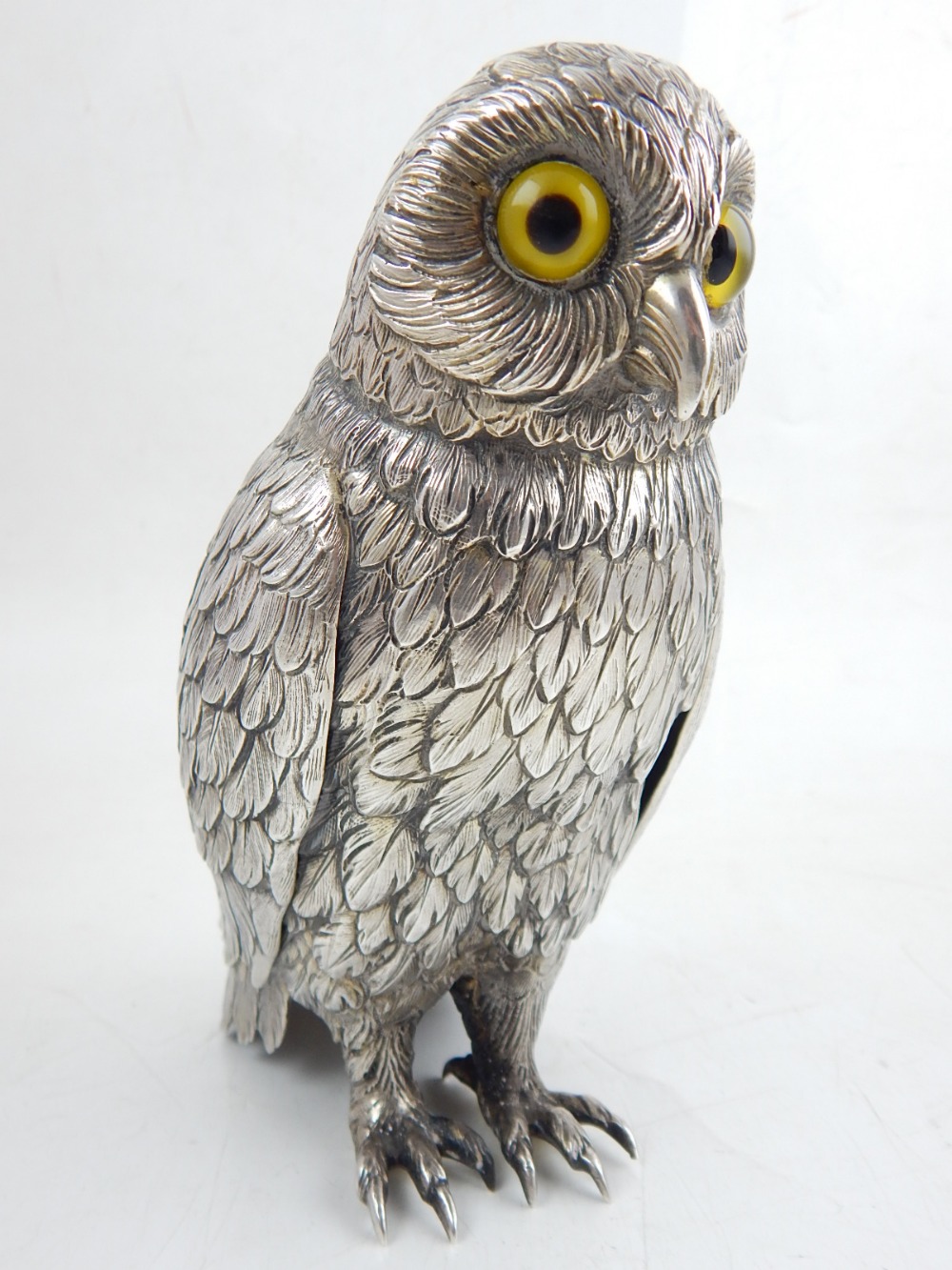 A Continental white metal desk piece modelled in the form of an owl, with detailed plumage and amber