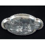 A 20th century Dutch white metal dish, repousse embossed with children dancing in a garden