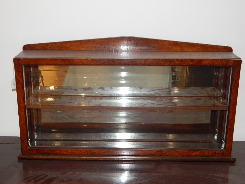 A Regency design birds eye maple wall display cabinet, with arched pediment over a glazed fall