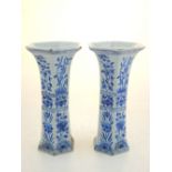 A pair of Delft blue and white pottery vases of tapered hexagonal form, painted with panels of