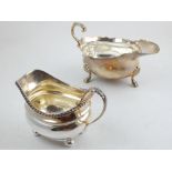 A George III silver cream jug with gadrooned rim, together with a later silver sauce boat with C-