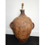 A 19th century Mediterranean pottery twin-handled oil jar, converted to a lamp. H. 60cm