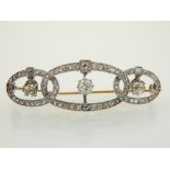 An early 20th century yellow metal diamond brooch of triple flattened hoop form each centered with