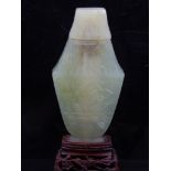A Chinese green hardstone snuff bottle, raised on a hardwood stand, H.16cm.