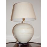 A Modern porcelain table lamp, cream ground of bulbous form, raised on carved wooden stand. H.