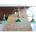 A tubular brass three branch billiard table light with conical green glass shades. L. 110cm