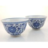 A pair of Chinese blue and white porclain tea bowls, decorated with scrolling foliage, bears seal