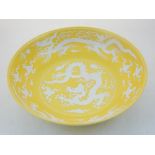 A Chinese yellow ground porcelain dish, decorated in white with dragons chasing flaming pearls