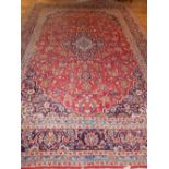 A Kashan blue ground carpet woven central lobed floral medallion within a conforming field and