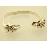 A silver torque bangle the cast leopard head, topaz set terminals with ruby eyes.