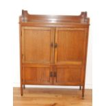 An Edwardian oak side cabinet, the top with a three quarter gallery above two pairs of panel doors,