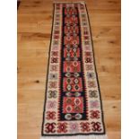 A Kazak kilim runner, the central geometric panels on a black ground within geometric border. L.