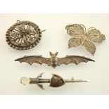 A silver bat wing brooch, a filigree brooch and two others.