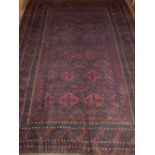 A Baluch carpet, decorated with octagonal medallions to centre within reticulated borders, fringed.