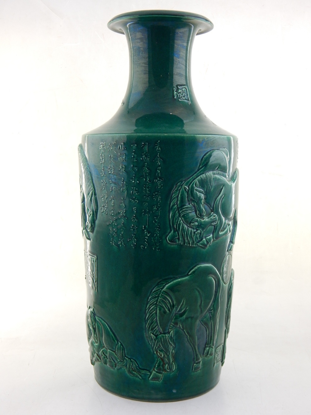 A Chinese green glazed porcelain vase, the body moulded with horses and script, H. 47cm.