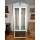 A large freestanding display cabinet, white and blue painted with a broken pediment and pair of