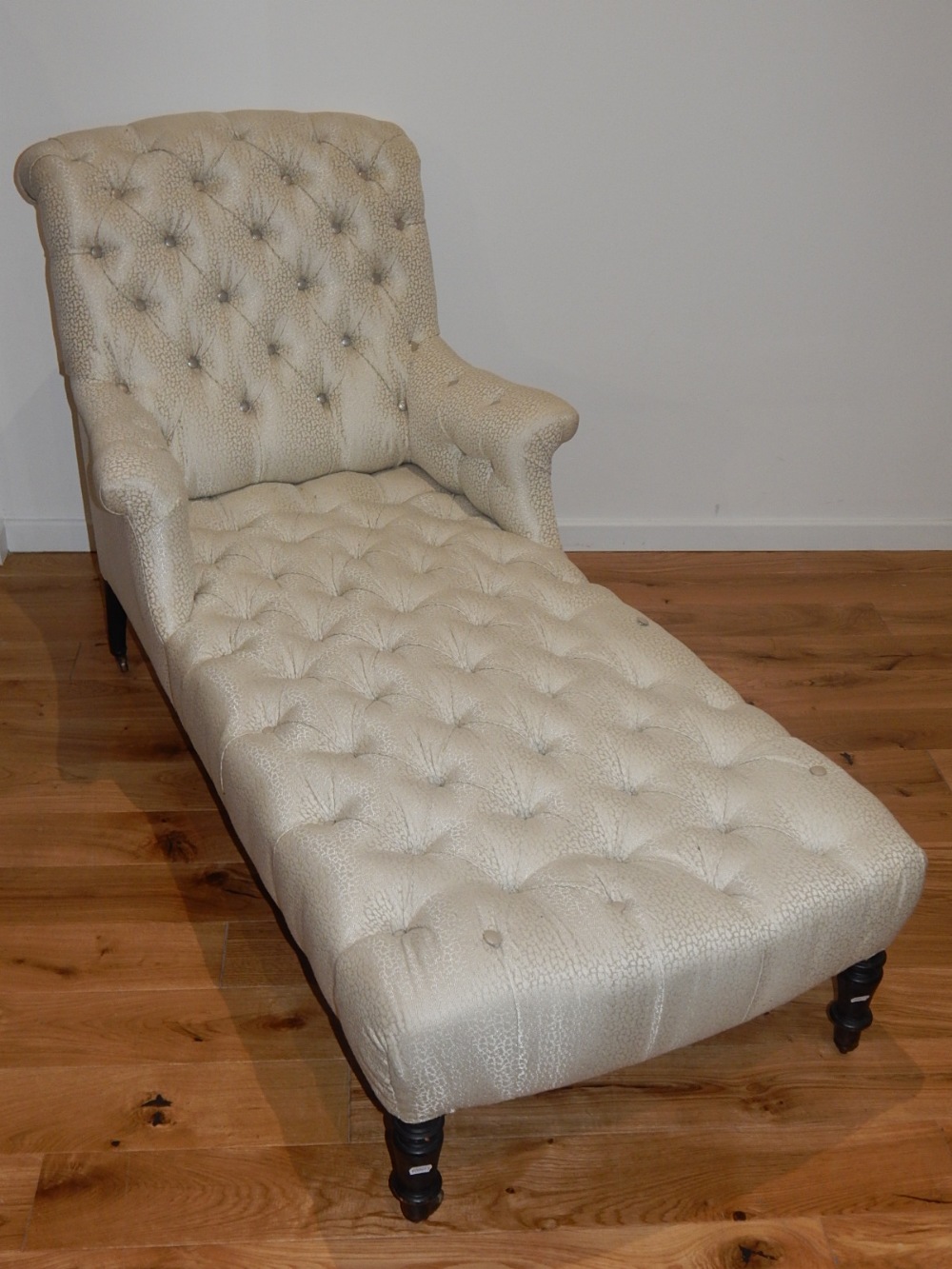 A 19th century daybed upholstered in deep buttoned silver / ivory fabric on turned tapered legs, L.