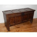 An 18th century oak coffer with four panel hinged top and front divided by a fluted frieze on