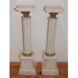 A pair of white marble columns, the square tops above gilt mounts and cluster columns on stepped