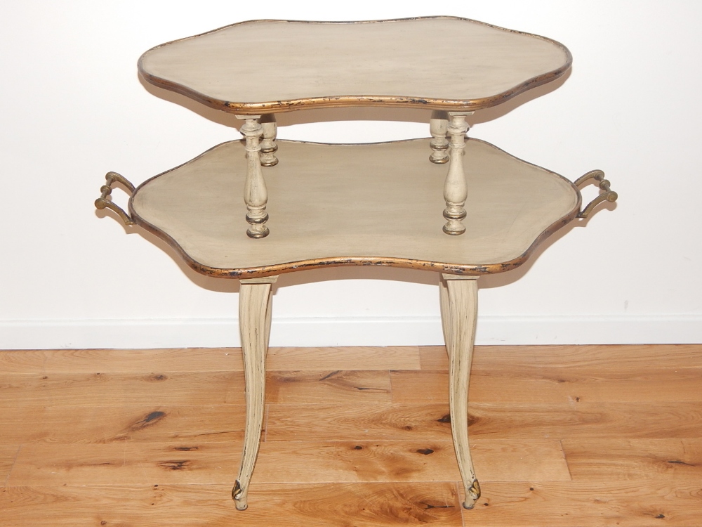 A two tier occasional table, the shaped oval tiers with a pair of carrying handles, on moulded legs,