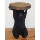 A German style bear occasional table modelled seated holding a faux tree section, H. 48cm.