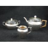 An early 20th century German silver three piece tea set, fluted rib body, rattan covered handles,