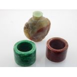 Two Chinese jade archer's rings, and a jade snuff bottle with dragon carving to shoulders. W. 5cm (