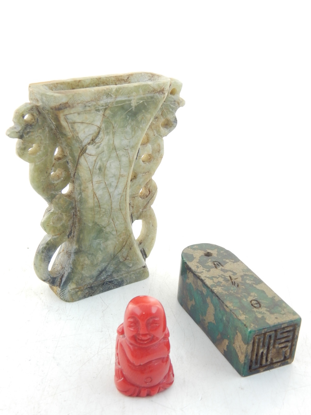 A Chinese carved red coral figure of a plump Buddha, together with a jade pedestal seal, and a