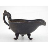 A Chinese bronze oil boat, dragon handle, floral decoration, tri-scroll feet. L. 12.5cm