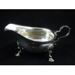 A modern Georgian design silver sauce boat with scroll handle on shell cast feet.