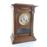 An early 20th oak cased mantel clock, the case with a swag and twin columns, the silvered dial set