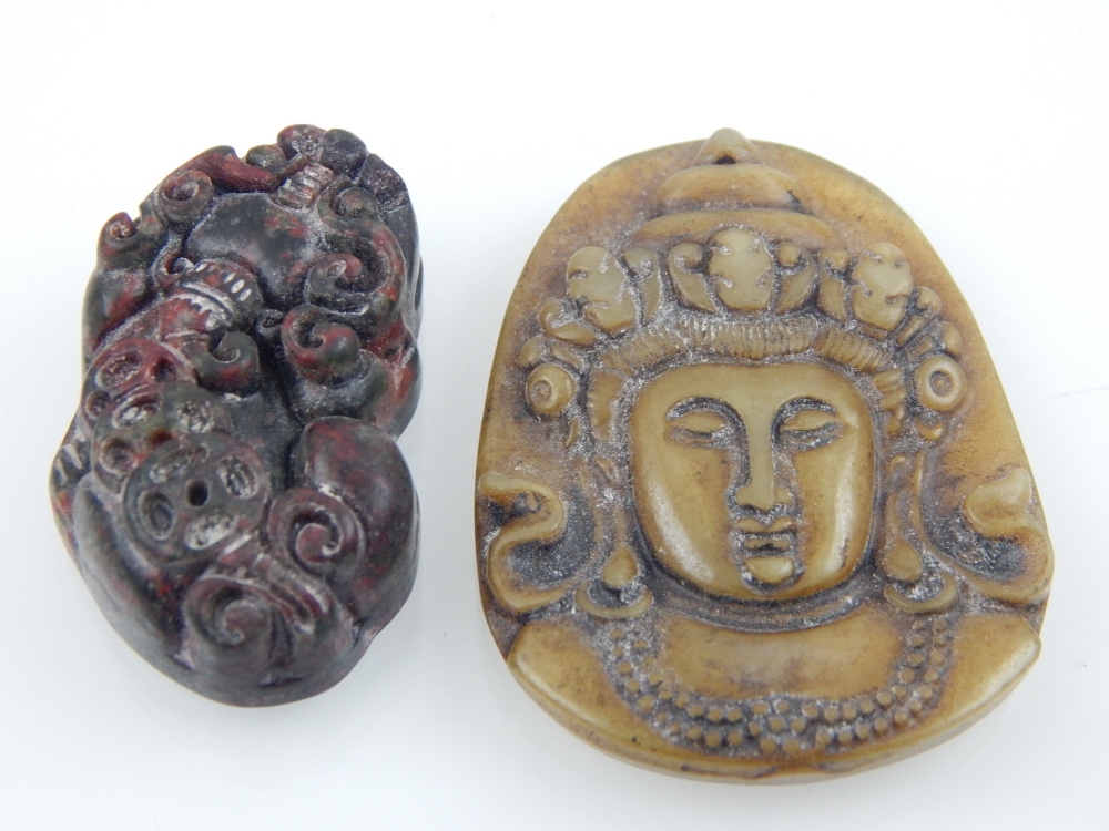 A Chinese spinach jade pendant carving of a god's face, H. 4.8cm, and a red / black jade pendant