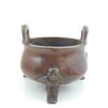 A Chinese bronze twin-handled circular pot bellied bowl, modelled as infants, on three feet, with