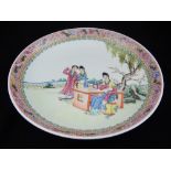 A Chinese famille rose circular porcelain dish, decorated with female figures in a garden landscape.