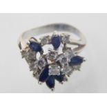 A white metal diamond and sapphire flower head cluster dress ring, high claw set with pierced