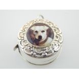 A silver tape measure, the top with plaque depicting a dog within embossed flowers. D. 3cm