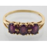 A 9ct yellow gold and three stone synthetic amethyst ring.