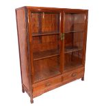 A Chinese glazed hardwood two door display cabinet, fitted two drawers over a carved geometric