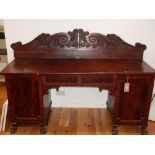 A William IV mahogany pedestal sideboard, the carved panelled back over twin panelled doors, on