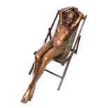 A life size patinated bronze figure of a nude lady sunbathing in a deck chair. L. 155cm